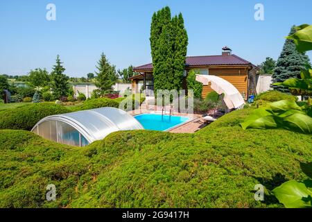 Garten mit schön getrimmten Büschen und Steinen und Schwimmbad im Hinterhof Stockfoto