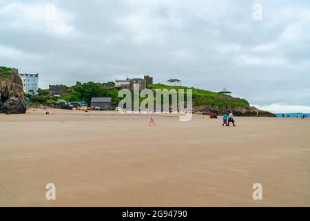 TENBY, WALES - 28. JUNI 2021: In Tenby im Südwesten von Wales schlendern die Menschen an einem Sandstrand entlang. Stockfoto