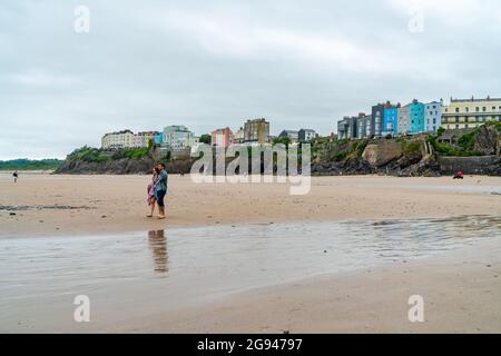 TENBY, WALES - 28. JUNI 2021: In Tenby im Südwesten von Wales schlendern die Menschen an einem Sandstrand entlang. Stockfoto