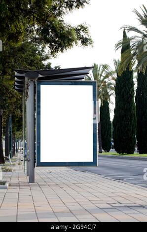 Vertikale leere Plakatwand auf der Stadtstraße mit grünen Bäumen Stockfoto