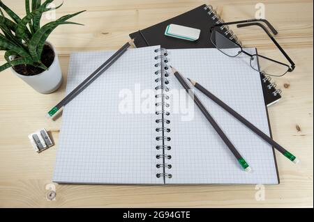 Home Office Schreibtisch für Arbeit, Studium und Schule mit einem leeren Spiralheftchen und Schreibwaren auf einem Holztisch, Kopierraum, ausgewählter Fokus, schmal Stockfoto