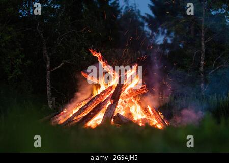 Brennendes Feuerholz mit einer orangen Flamme in einem Lagerfeuer. Stockfoto