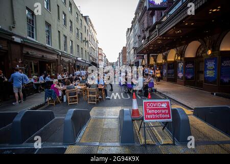 Menschen in einem Restaurant werden hinter einem Schild mit „vorübergehenden Zwangsbeschränkungen“ im Londoner Stadtteil Soho gesehen, das alle Einschränkungen des täglichen Lebens in England aufhebt. Stockfoto