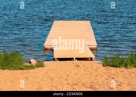 Hölzerne Pier (Brücke) erstreckt sich vom Strand bis zum türkisfarbenen Wellenmeer Stockfoto