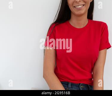 T-Shirt-Modell, Vorderansicht einer nicht erkennbaren Frau mit rotem T-Shirt. Kopieren Sie Platz auf leeren Bereich auf ihrem T-Shirt für Design oder Beschriftung. Fashion Lifestyle-Modell aus rotem T-Shirt. T-Shirt-Vorlage. Stockfoto