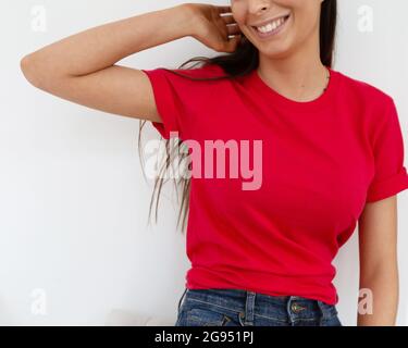 T-Shirt-Modell, Vorderansicht einer nicht erkennbaren Frau mit rotem T-Shirt. Kopieren Sie Platz auf leeren Bereich auf ihrem T-Shirt für Design oder Beschriftung. Fashion Lifestyle-Modell aus rotem T-Shirt. T-Shirt-Vorlage. Stockfoto