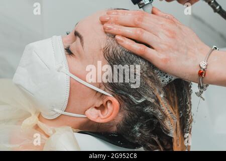 Die Frau in einem Friseurladen färbt ihre Haare und wäscht ihren Kopf während des Färbens ihrer Haare. Neu Stockfoto