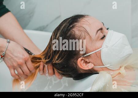 Die Frau in einem Friseurladen färbt ihre Haare und wäscht ihren Kopf während des Färbens ihrer Haare. Neu Stockfoto