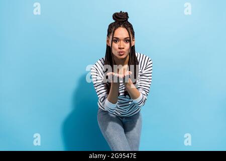 Foto von jungen fröhlich afro Mädchen pouted Lippen senden Luft Kuss Sie kokett romantisch isoliert über blauen Hintergrund Stockfoto