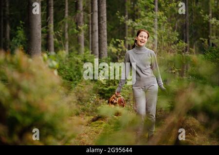 Eine Frau geht im Wald spazieren und sammelt Pilze Stockfoto