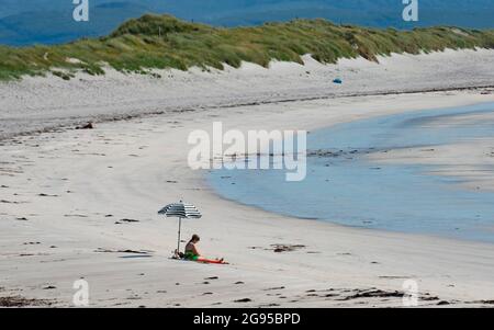 Benbecula, Äußere Hebriden, Schottland, Großbritannien. 24. Juli 2021. Wenn an einem anderen heißen, sonnigen Wochenendtag an den Stränden im Vereinigten Königreich Sonnenanbeter voll sind, genießt eine einsame Frau den weißen Sand an einem leeren, wunderschönen Strand an der Westküste von Benbecula in den Äußeren Hebriden in Schottland, Großbritannien. Iain Masterton/Alamy Live Nachrichten. Stockfoto