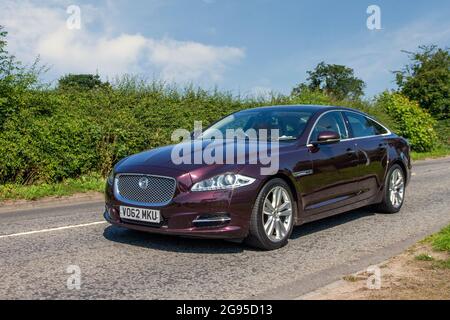 Der rote Jaguar XJ Premium Luxury V6 D A aus dem Jahr 2012 auf dem Weg zur Capesthorne Hall Classic Car Show im Juli in Ceshire, Großbritannien Stockfoto