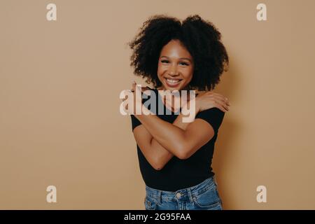 Bild von schönen zufrieden jungen dunkelhäutigen Weibchen mit voluminösen Afro Frisur Stockfoto