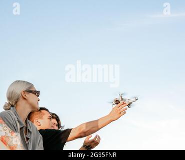 Junger Mann fängt eine Drohne, während Freunde sie beobachten Stockfoto