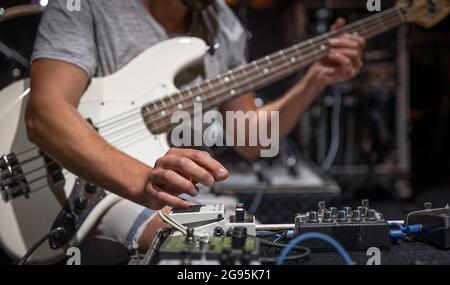 Ein männlicher Gitarrist, der auf der Bühne Audio-Verarbeitungseffekte für die Gitarre einspielt. Stockfoto