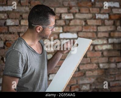 Der Zimmerer wertet das Bohrergebnis im Brett aus Stockfoto