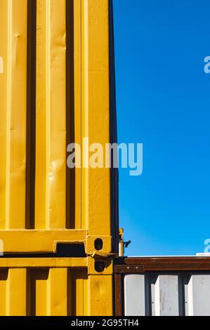 Vertikales abstraktes Bild von gestapelten gelben Transportbehältern vor einem klaren blauen Himmel Stockfoto