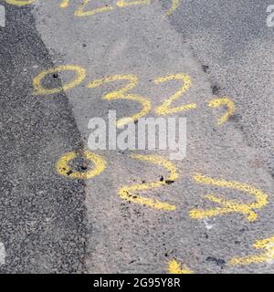 Gelbe Farbsprühmarkierungen auf einer kleinen asphaltierten Fahrbahn. Gelb ist in der Regel für gasassoziierte Arbeiten bestimmt, aber unsicher, ob dies hier der Fall ist. Stockfoto