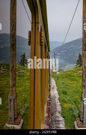 Schynige Platte, Berner Oberland, Schweiz - Touristischer Zahnradwagen mit rotem Zug in atemberaubendem Panorama mit Schweizer Alpen und Brienzersee Stockfoto