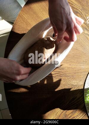 Der Bäcker legt den Roggenteig in den Korb Stockfoto