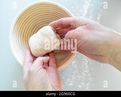 Der Bäcker legt den Teig in einen Korb mit Rottan Stockfoto