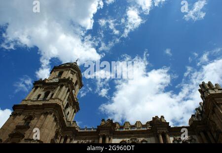 Die wunderschöne Kathedrale der historischen Stadt Malaga. Winkelansicht des Glockenturms mit verzierten, dekorativen Schnitzereien. Blauer Himmel und Wolken - Kopie s Stockfoto