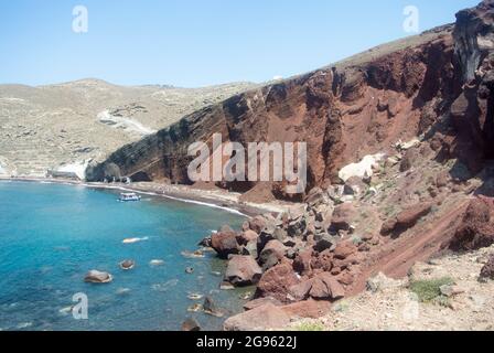 Ein Blick auf die schroffen vulkanischen Klippen auf der Ferieninsel Santorini. Roter Strand an der Südküste. Geologische Formationen aus alten Eruptionen der Stockfoto