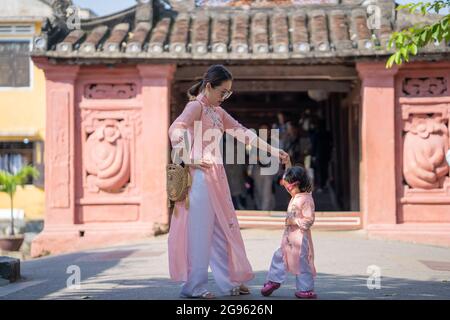 Junge asiatische Mutter in ähnlichen Kleidern mit ihrer Tochter Zeit mit ihr während eines Urlaubs gekleidet Stockfoto