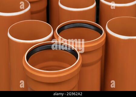 Stapel von PVC-U-Kanalisationsrohren auf einem Eisenwarenlager. Braune Kunststoffrohre. Industrie für Außenhof. Baumaterialien, Stockfoto