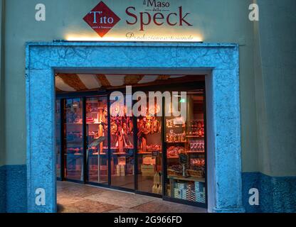 Trient, Italien, Juni 2021. Das appetitliche Fenster eines Trentiner Spezialitätenladens: Speck, Schinken, Salami werden so ausgestellt, dass Kunden angezogen werden. Stockfoto