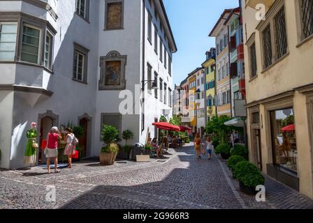 Bozen, Italien, Juni 2021. Eine Nebenstraße im historischen Zentrum. Menschen auf der Straße, helle, warm gefärbte Fassaden im Hintergrund. Wunderschön Stockfoto