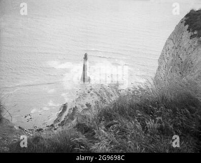 1950s, historisch, der Offshore-Leuchtturm am Fuße der Bucht von Beachy Head, einer berühmten Landzunge an den South Downs in Eastbourne, East Sussex, England, Großbritannien. Ein Granit-Turm, der 1902 errichtet wurde, um den Leuchtturm der Belle Tour auf der Spitze der Klippen zu ersetzen, war der letzte traditionelle „Felsturm“, der in England gebaut wurde. Beachy Head, die höchste kalkförmige Meeresklippe Großbritanniens, und die umliegenden hügeligen Abfahrten sind ein wunderschöner Ort für Spaziergänge. Im Jahr 1929 wurde durch einen Akt des Parlaments das Land an den South Downs gekauft, um seine Nutzung für zukünftige Generationen zu sichern. Stockfoto