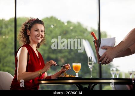 Champagner im Kühler mit Eis zu einer jungen Frau im Restaurant bringen Stockfoto