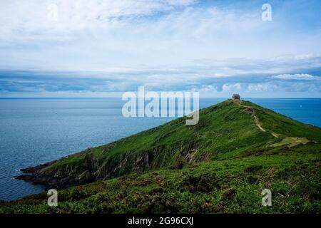 Touristen wandern zur und von der Rame Head Chapel über eine felsige Landzunge Stockfoto