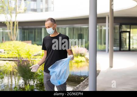 Mann, der im Park Hausmüll aus Plastik abholt Stockfoto