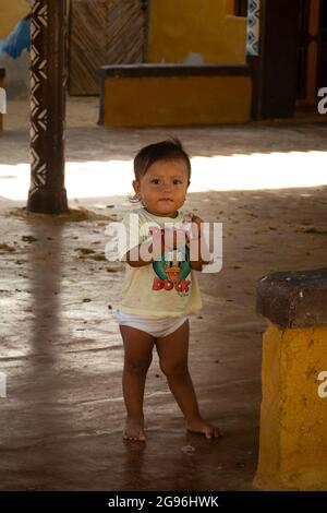 Uribia, La Guajira, Kolumbien - 28 2021. Mai: Glückliches Wayuu-Mädchen, das in einem offenen Klassenzimmer in Windeln läuft Stockfoto