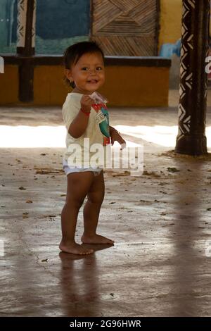 Uribia, La Guajira, Kolumbien - 28 2021. Mai: Glückliches Wayuu-Mädchen, das in einem offenen Klassenzimmer in Windeln läuft Stockfoto