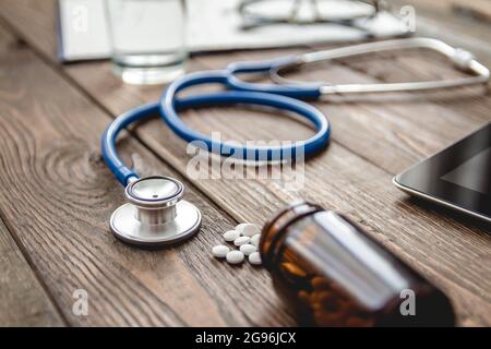 Nahaufnahme der Krankenkarte des Patienten, Stethoskop und Pillen auf dem Arzttisch Stockfoto