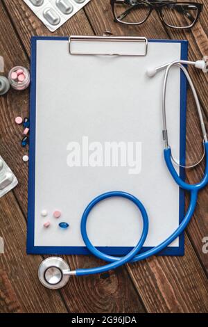 Nahaufnahme der Krankenkarte des Patienten, Stethoskop und Pillen auf dem Arzttisch Stockfoto