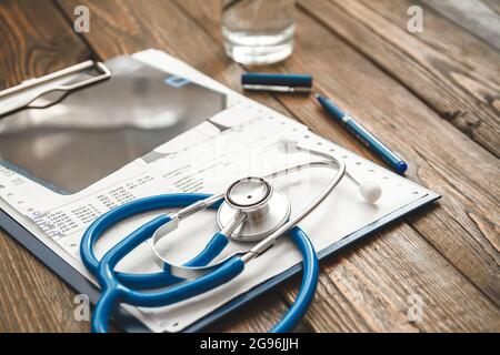 Nahaufnahme der Krankenkarte des Patienten, Stethoskop und Pillen auf dem Arzttisch Stockfoto