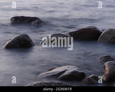 Glatte Granitsteine im Meerwasser lange Exposition Stockfoto