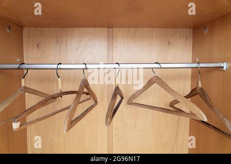 Kleiderbügel aus Holz, die in einem alten Kleiderschrank aus nächster Nähe hängen Stockfoto