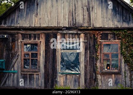 Fassade mit Fenstern eines sehr alten verfallenen Holzhauses Stockfoto