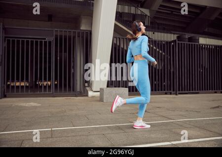 Schlanke junge kaukasische Dame macht Sport im Freien in der Stadt Stockfoto