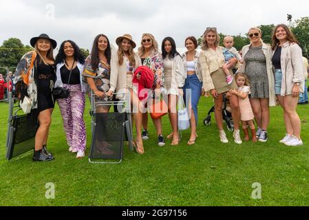 Promenade Park, Maldon, Essex, Großbritannien. Juli 2021. Bei einem der ersten Events dieser Art, nachdem die britischen COVID-19-Beschränkungen aufgehoben wurden, sind die Fans angekommen, um ein großes Musikfestival in einem Park in Essex zu genießen. Die 80er-Jahre-Lieblingsbands sind auf der Bühne vor rund 10,000 Nachtschwärmern als Headliner eines Tages zu sehen. DJs unterhalten die Massen, während sie auf die Live-Acts warten. Glückliche Leute, die nach der Sperre bei der Veranstaltung ankamen. Gruppe junger Freundinnen Stockfoto