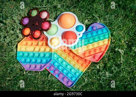 Einige Pop-it-Spielzeuge liegen auf grünem Gras, popit und einfache Grübchen-Spiel für Anti-Stress-Aktivitäten Stockfoto