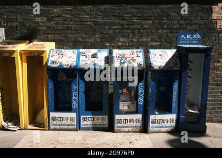 Leere kostenlose chinesische Zeitungsstände mit Graffiti und Aufklebern auf der Straße in Chinatown, Soho, London, Großbritannien. Stockfoto