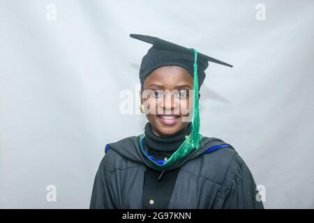 Porträt einer glücklichen afrikanischen Graduierten oder Absolventen lächeln in ihrem schwarzen Outfit Stockfoto