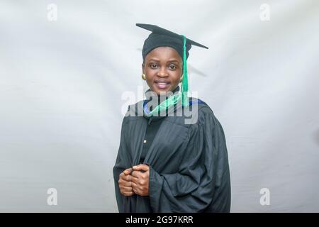 Porträt einer glücklichen afrikanischen Graduierten oder Absolventen lächeln in ihrem schwarzen Outfit Stockfoto