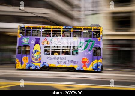 Eine Straßenbahn fährt entlang der des Voeux Road, Central, Hong Kong Island, in einer Schwenkaufnahme mit selektiven Bewegungsunschärfen aufgrund von Kamerabewegungen Stockfoto